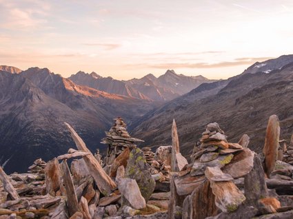 Hiking in Matrei am Brenner Stone cairns on mountain with sunset in the Alps