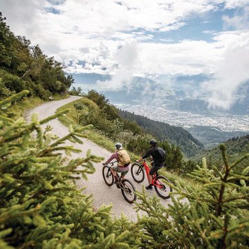 Neuigkeiten aus dem Motorradhotel in Tirol Zwei Radfahrer auf einem Bergweg mit Blick auf Tal und Wolken