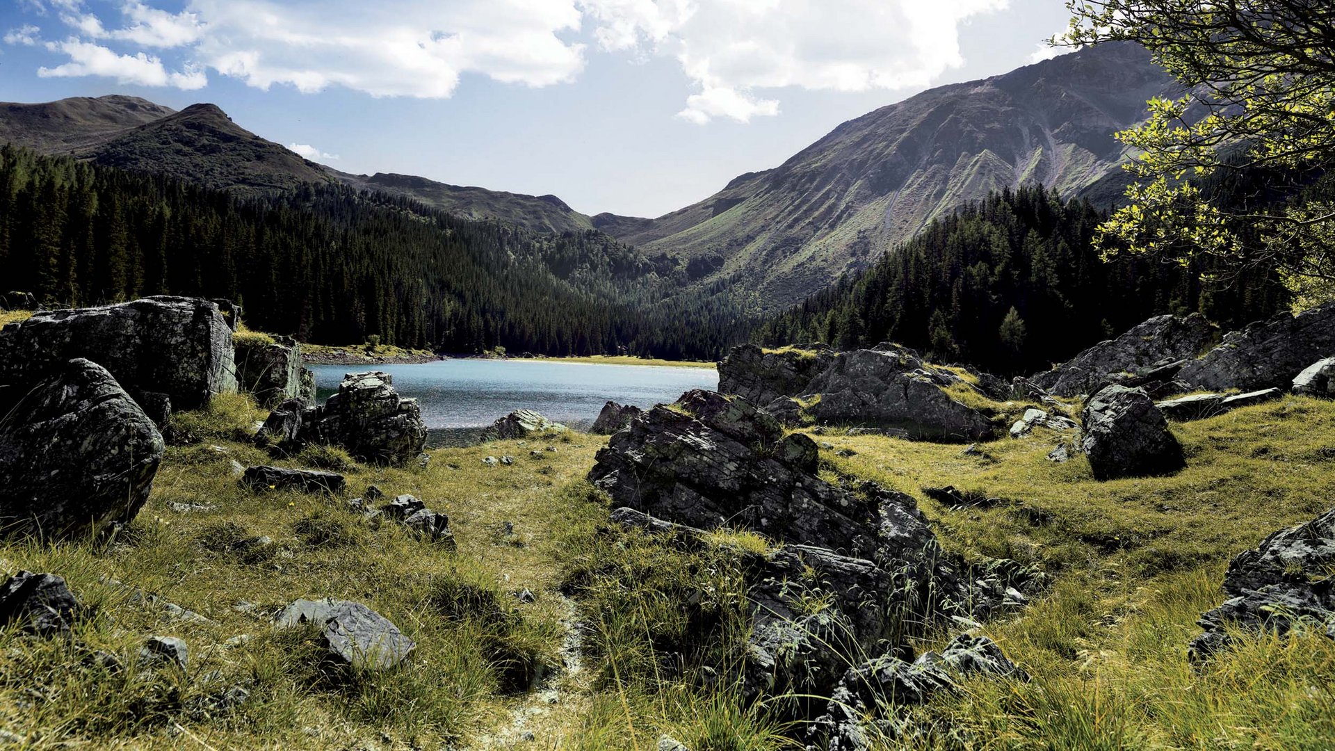Berglandschaft mit See, Felsen und bewölktem Himmel