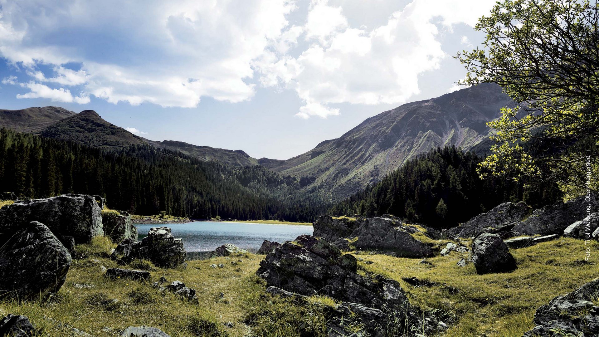 Paesaggio montano con lago, rocce e cielo nuvoloso