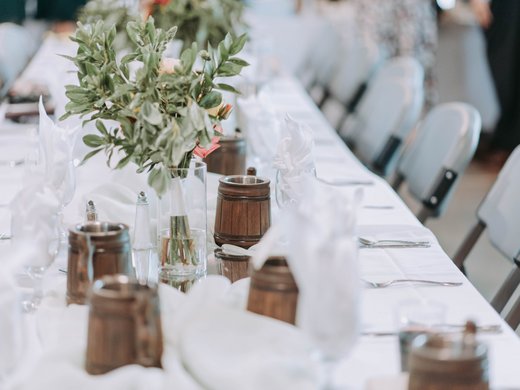 Your event in our hotel near the Brenner motorway Long table with white tablecloth, flower vase, and wooden mugs for event