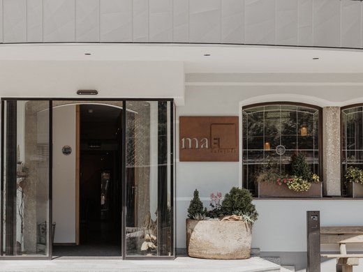 Zentrales und gemütliches Hotel am Brenner | Parkhotel Matrei Eingang zum Café Bar mit großen Glasflügeltüren und Blumentöpfen