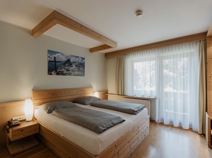 Kurzurlaub in Tirol? Ja, bitte! Hell eingerichtetes Schlafzimmer mit Doppelbett und Fenster mit Gardinen