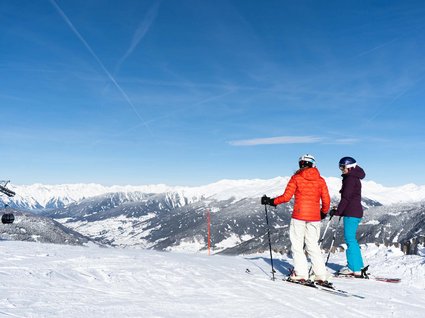 Settimana bianca nel comprensorio dello Stubai e altro Due sciatori con attrezzatura guardano le montagne innevate sotto un cielo terso