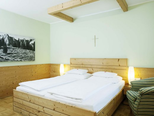 Hotel vicino all’Autostrada del Brennero: comodo e bello Camera semplice con letto matrimoniale, pareti in legno e croce sulla parete