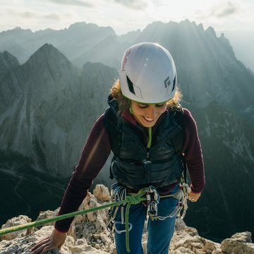 Neuigkeiten aus dem Motorradhotel in Tirol Klettererin mit Helm am Berg bei Sonnenlicht