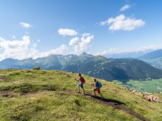 Zentrales und gemütliches Hotel am Brenner | Parkhotel Matrei Zwei Wanderer mit Rucksäcken gehen einen Bergpfad bei klarem Himmel entlang