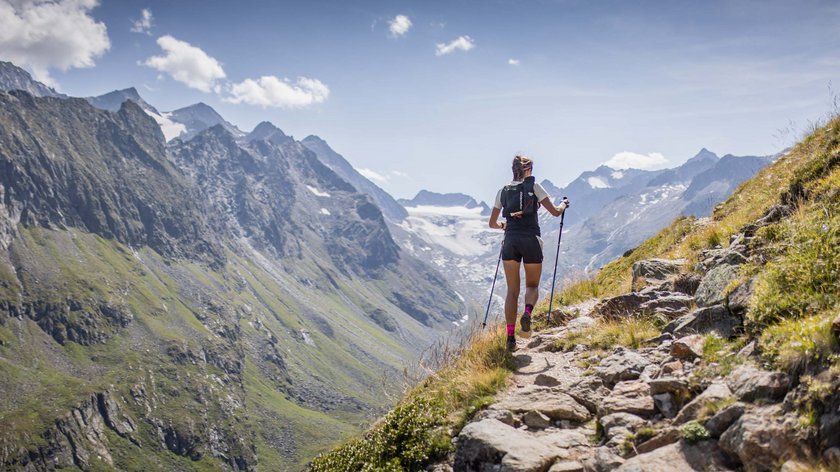 Traumlandschaft beim Wandern erkunden Frau wandert mit Stöcken auf einem Bergpfad in Alpenlandschaft