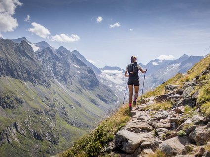 Hiking in Matrei am Brenner Woman hiking with poles on a mountain trail in the Alps
