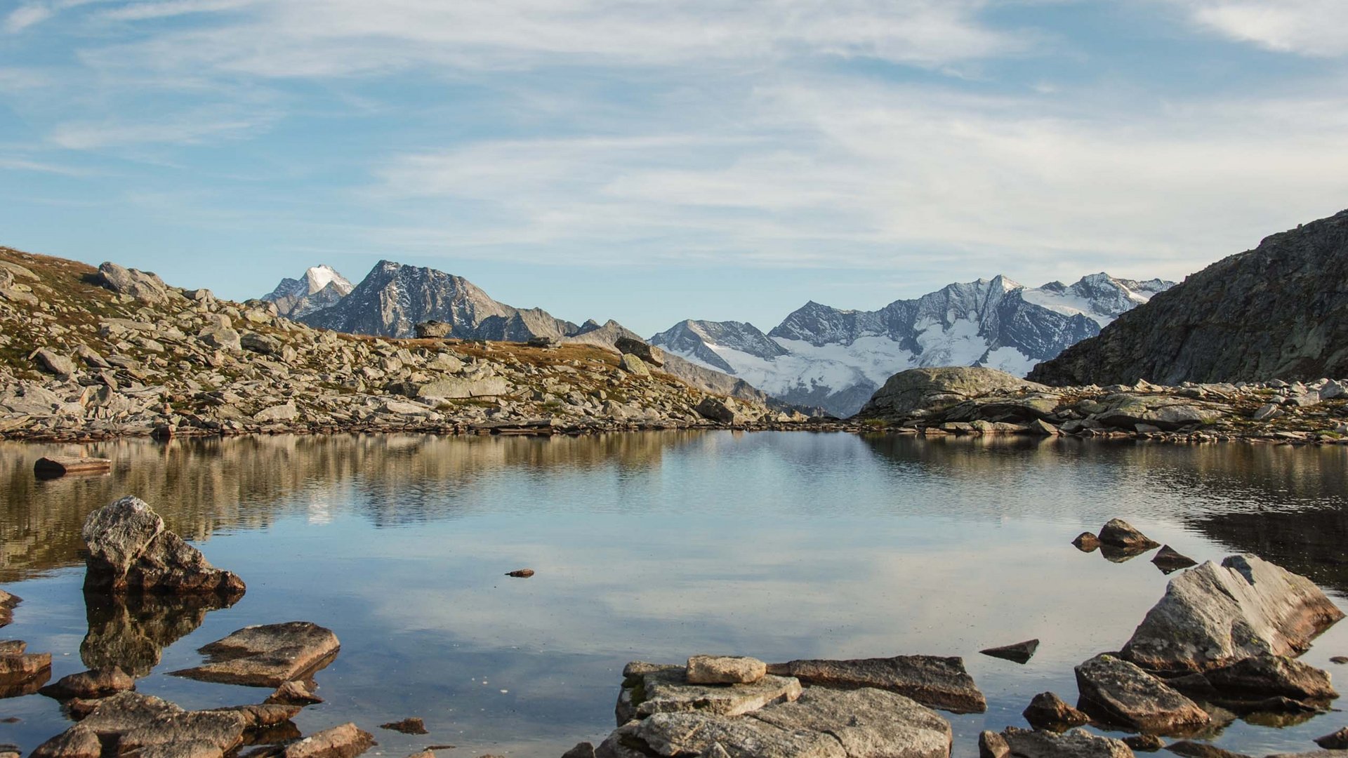 Paesaggio montano con lago e cime innevate sotto cielo limpido