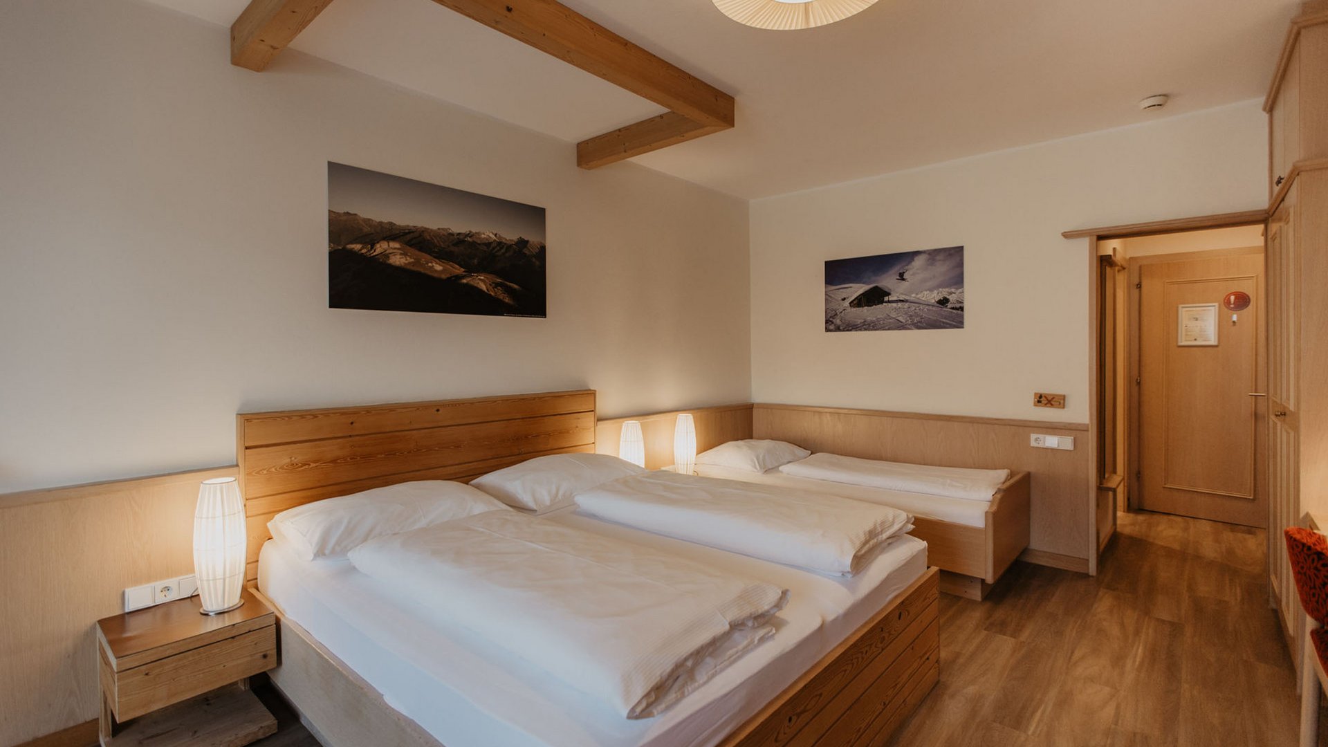 Hotel room with two single beds and one wooden double bed