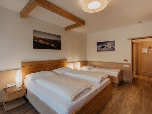 Übernachtung Nähe Brennerautobahn: zentral und trotzdem idyllisch Hotelzimmer mit zwei Einzelbetten und einem Doppelbett aus Holz
