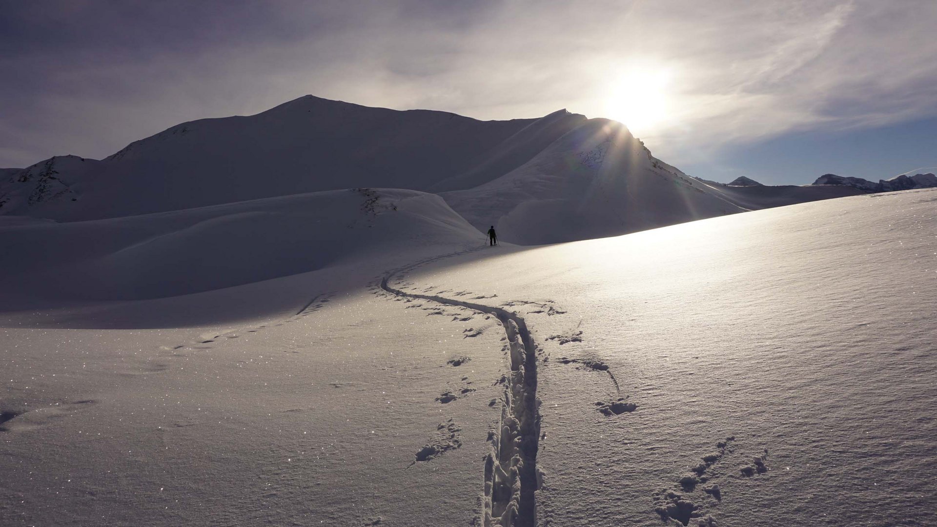 Attrazioni ed escursioni in Tirolo, Austria Tracce di sci sulla neve con montagna e sole sullo sfondo