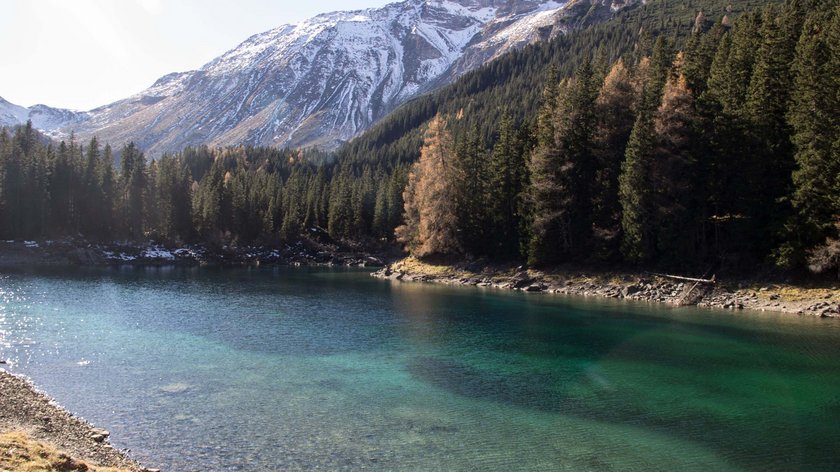 Wanderung zum Obernberger See Klarer Bergsee mit Nadelwald und schneebedeckten Bergen im Hintergrund