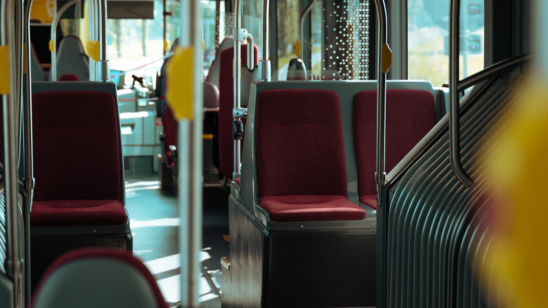 Empty bus interior with red seats and many handrails