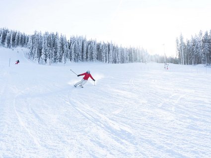 Settimana bianca nel comprensorio dello Stubai e altro Sciatore con giacca rossa scende una pista circondata da alberi innevati