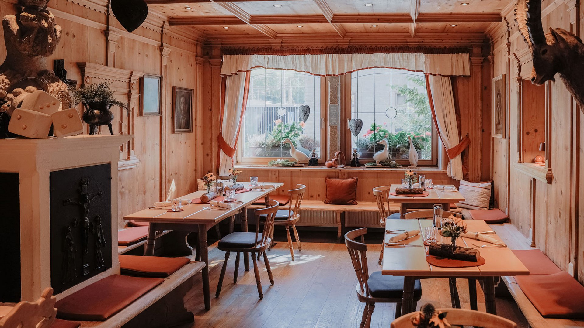 Kurzurlaub in Tirol? Ja, bitte! Gemütlicher Holzestraum mit Tischen und Stühlen in einem traditionellen Restaurant