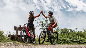 News (Liste) Zwei Radfahrer in Berglandschaft geben sich High Five