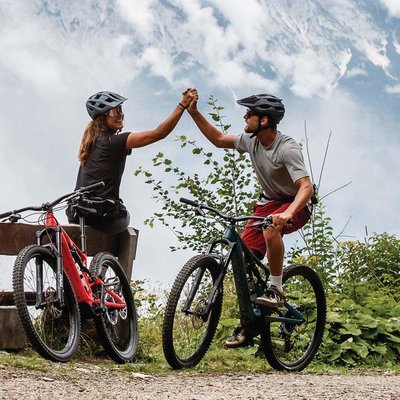 News (Liste) Zwei Radfahrer in Berglandschaft geben sich High Five