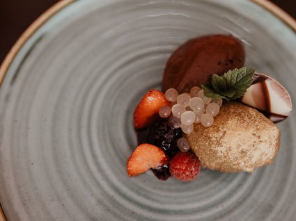 Hotel nella Wipptal, Austria con certificazioni ambientali Dessert gourmet con cioccolato, frutti di bosco e foglia di menta su piatto grigio