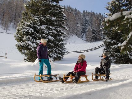 Alpi Aurine e Stubai: sci estivo ed escursioni Tre donne con slitte sulla neve davanti a alberi innevati