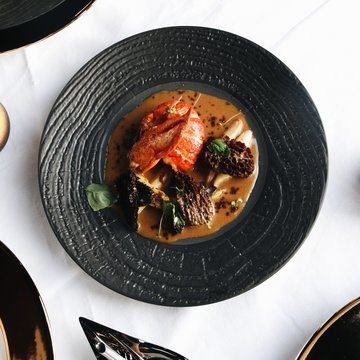 Deliciousness awaits in our restaurant in Matrei am Brenner Gourmet dish with lobster and mushrooms on black plate on white table