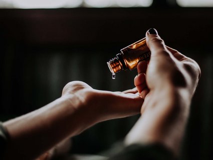 Das etwas andere Hotel in Tirol mit Wellnessbereich Hand tropft ätherisches Öl aus brauner Flasche auf andere Hand