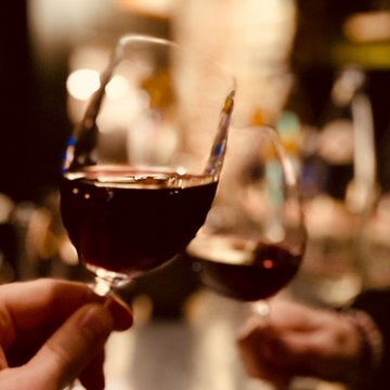 News & Tipps für den Österreich Wanderurlaub | Parkhotel Matrei Zwei Hände stoßen mit Rotweingläsern in einer Bar an