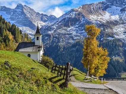Ausflugstipps aus unserem Hotel: Innsbruck und Umgebung kleine kapelle auf grasigem hügel mit herbstbäumen und schneebedeckten bergen