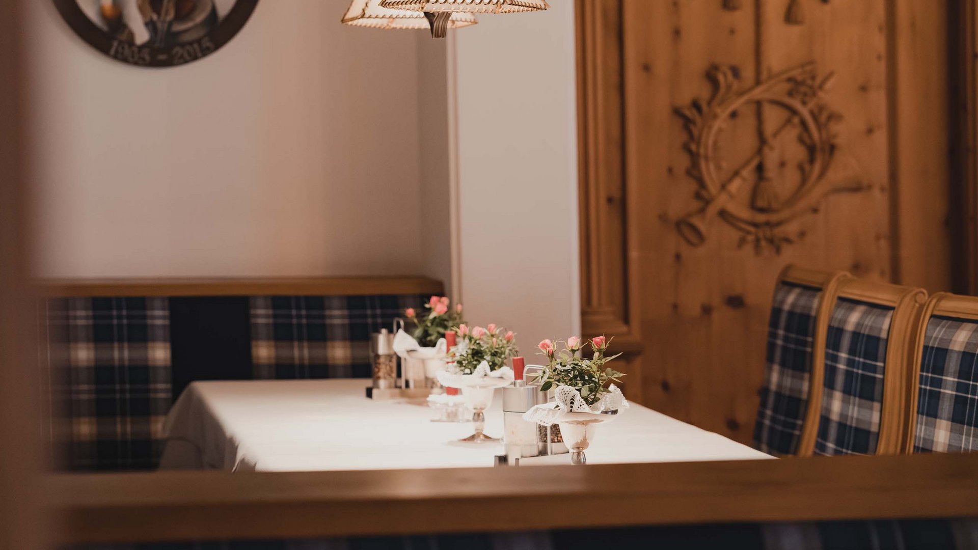 Gemütlicher gedeckter Tisch mit Blumen und karierten Sitzbänken in einem Restaurant