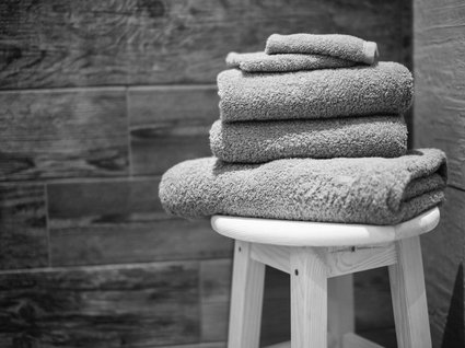 Das etwas andere Hotel in Tirol mit Wellnessbereich Gefaltete Handtücher auf einem Hocker vor einer Holzfliesenwand