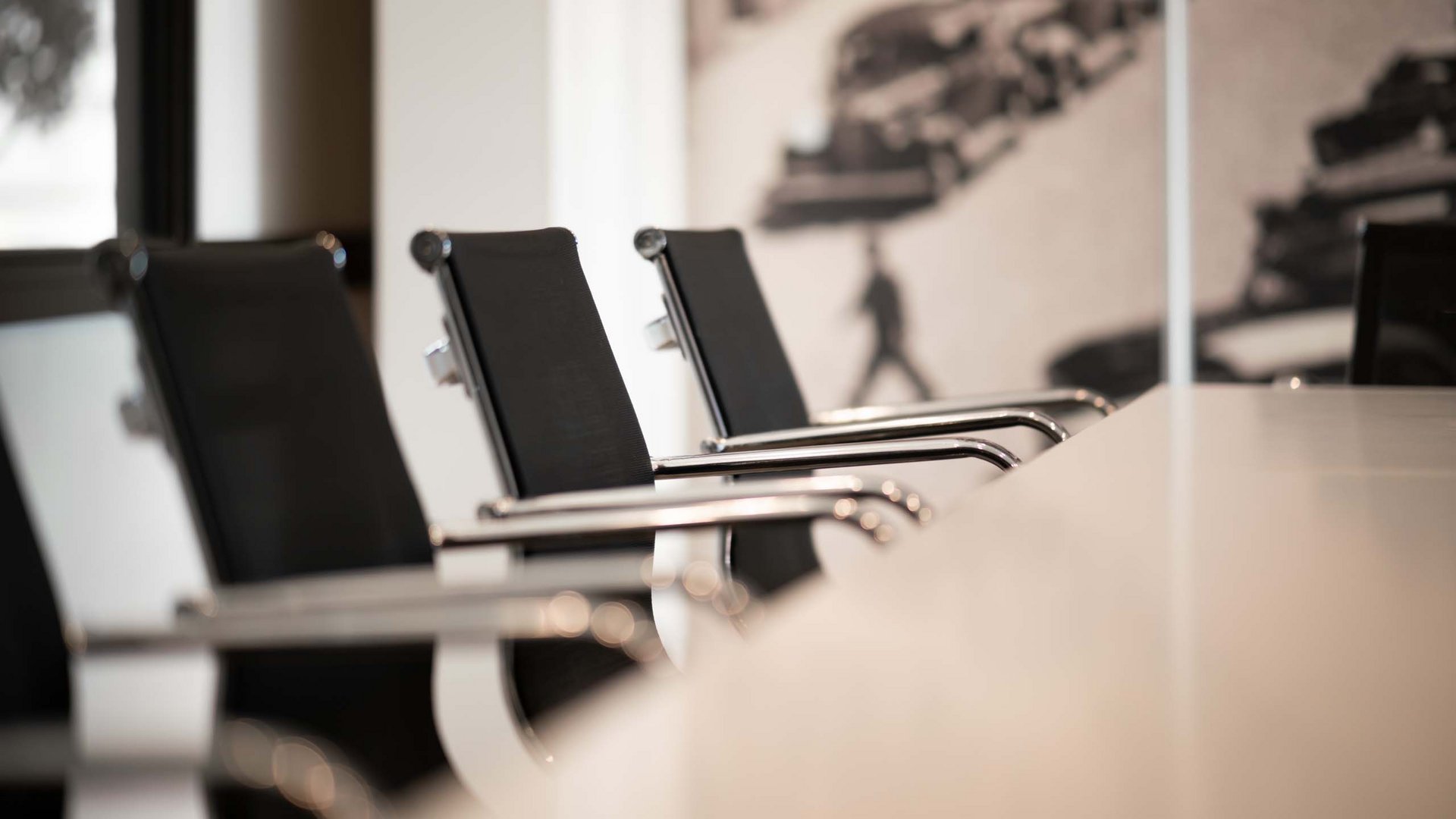Schwarze Bürostühle an einem weißen Konferenztisch in einem modernen Raum