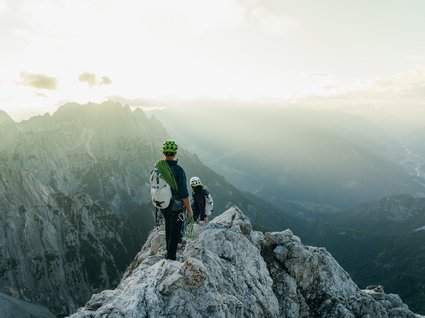 Holidays at the Brenner Pass: hiking and climbing Two climbers on a summit overlooking misty mountains at sunrise