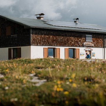 News & Tipps für den Österreich Wanderurlaub | Parkhotel Matrei Berghaus mit Solarpaneelen auf dem Dach und Blumenwiese im Vordergrund