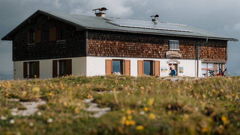 Bergtour auf die Blaserhütte Berghaus mit Solarpaneelen auf dem Dach und Blumenwiese im Vordergrund