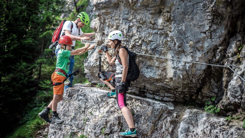Adrenalin und Emotionen Drei Personen beim Klettern an einer Felswand gesichert mit Helmen und Kletterausrüstung