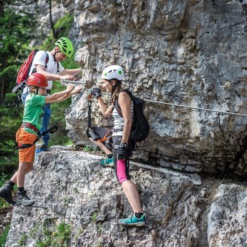 Neuigkeiten aus dem Motorradhotel in Tirol Drei Personen beim Klettern an einer Felswand gesichert mit Helmen und Kletterausrüstung