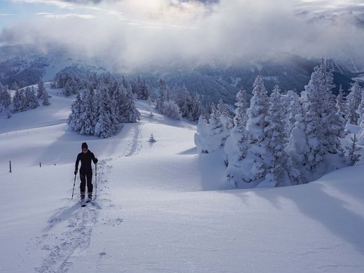 Dein Hotel im Wipptal: herzlich willkommen! Skifahrer wandert durch verschneite Berglandschaft unter bewölktem Himmel