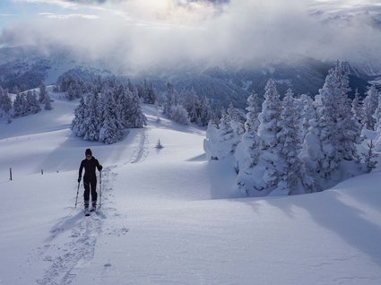 Die schönsten Skitouren in Tirol Skifahrer wandert durch verschneite Berglandschaft unter bewölktem Himmel